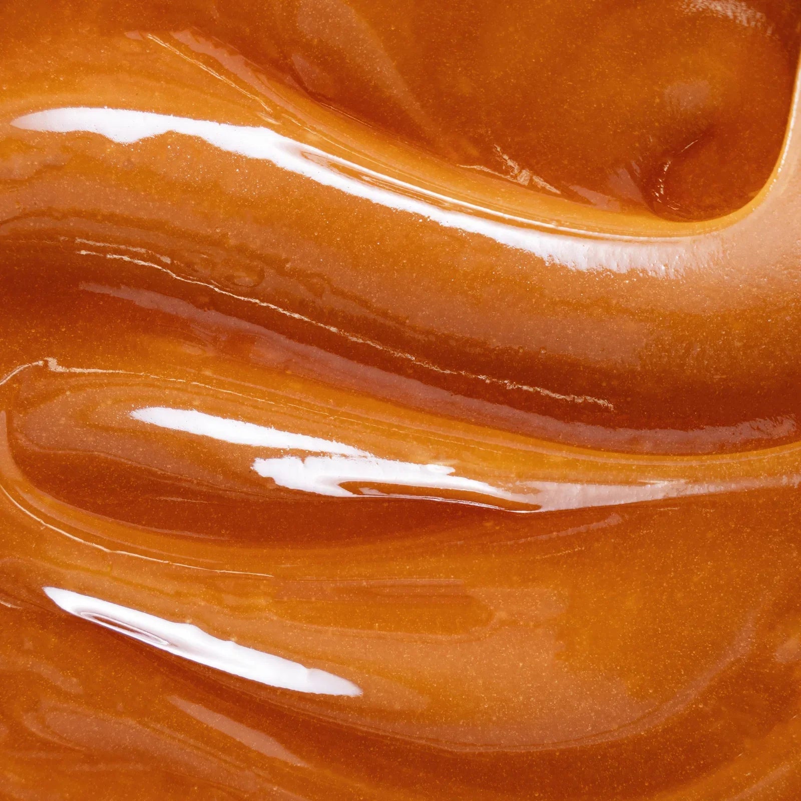 Close-up of glossy orange nail polish with white streaks and highlights on curved nail surface.